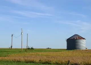 Photo of a field with a grain storage bin and power line poles