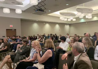 many people gathered watching a lecture, clapping