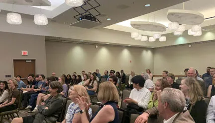 many people gathered watching a lecture, clapping