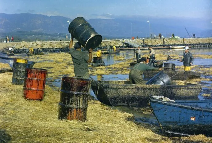 people cleaning up an oil spill on very polluted waters