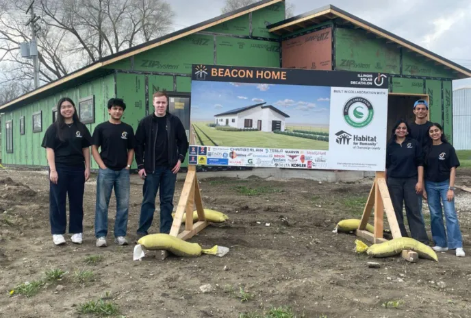 Students standing next to the the Beacon project poster in front the house: Chambana Today