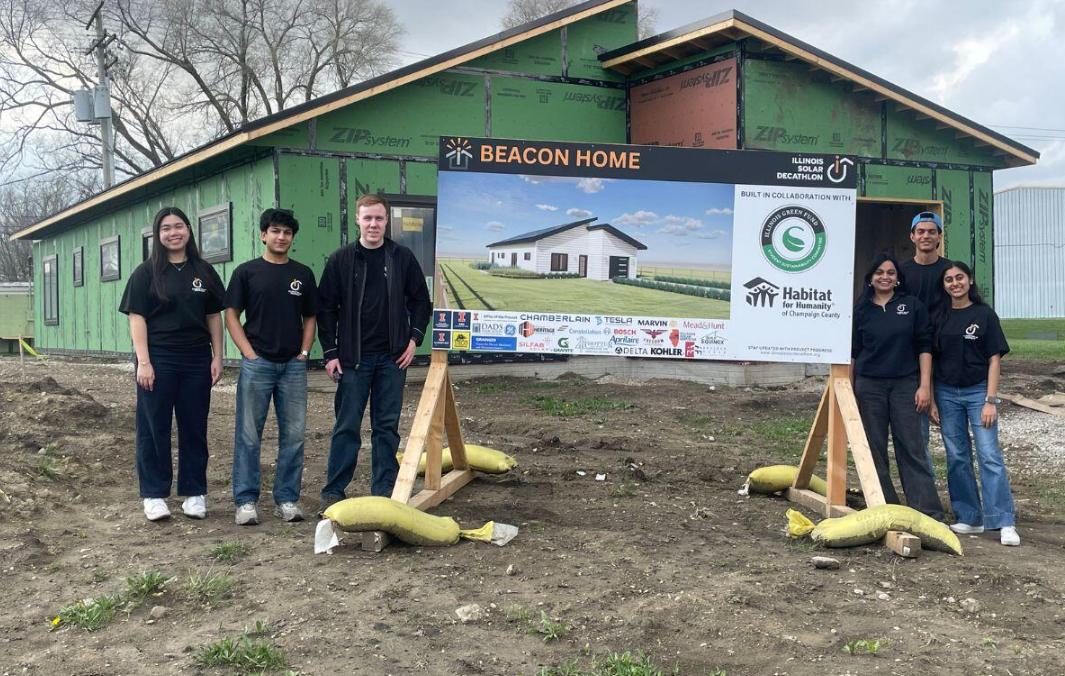 Students standing next to the the Beacon project poster in front the house: Chambana Today
