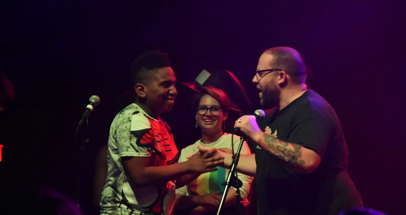 3 people standing around a microphone.