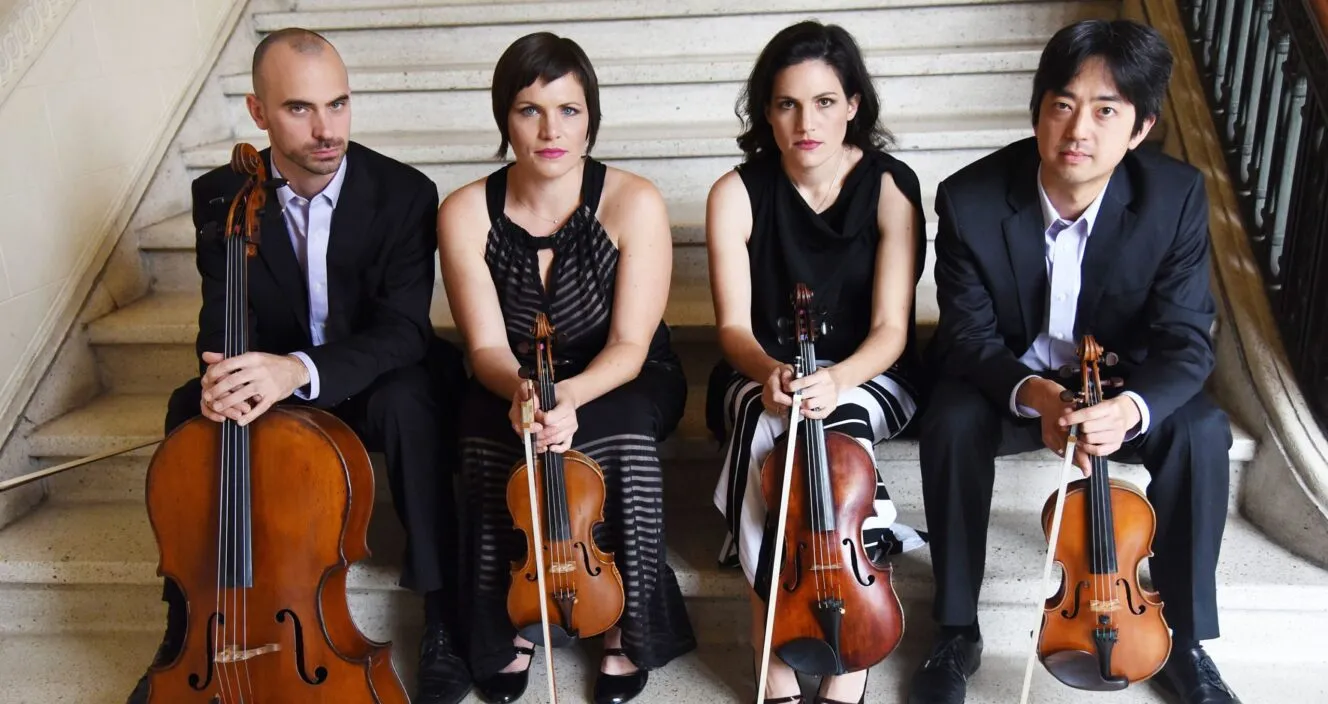 4 members of the Jupiter Quartet sitting on steps, holding their instruments.