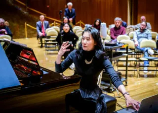 person sitting at piano gestures with their hands while talking