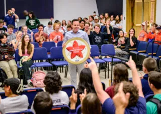 Marching Illini director Barry Houser announces to band members that they will perform in the 100th Macy’s Thanksgiving Day Parade in 2026, one of 10 marching bands selected from more than 100 applicants. The band assembled at the Harding Band Building to hear the historic news. This will be Marching Illini’s second appearance in the parade, with the first being in 2015. Photo by Fred Zwicky