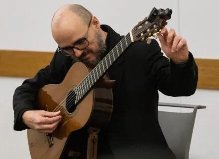 Dr. Guido Sánchez-Portuguez, assistant professor in FAA, tunes his acoustic guitar during his concert performance at the Champaign Public Library on Jan. 30.  Photo by Sarah Slattery, The Daily Illini