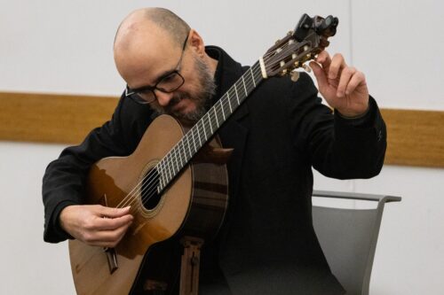 Dr. Guido Sánchez-Portuguez, assistant professor in FAA, tunes his acoustic guitar during his concert performance at the Champaign Public Library on Jan. 30.  Photo by Sarah Slattery, The Daily Illini