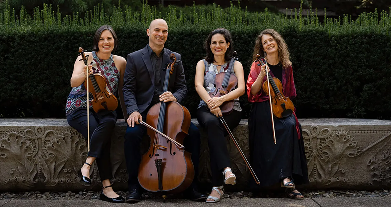 4 members of the Jupiter Quartet sitting on steps, holding their instruments.