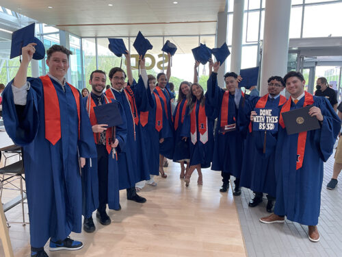 BSSD students stand in hald circle dressed in blue and orange graduation regalia