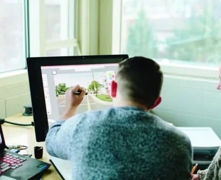 an instructor uses touch screen computer to show student how to improve roadway design