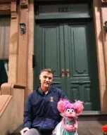 Paul Rudolph on the steps of the Sesame Street set with Abby Cadabby