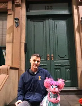 Paul Rudolph on the steps of the Sesame Street set with Abby Cadabby