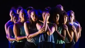 many dancers gatherd in dark blue lighting in embrace