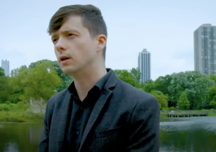 person standing in front of lake and cityscape