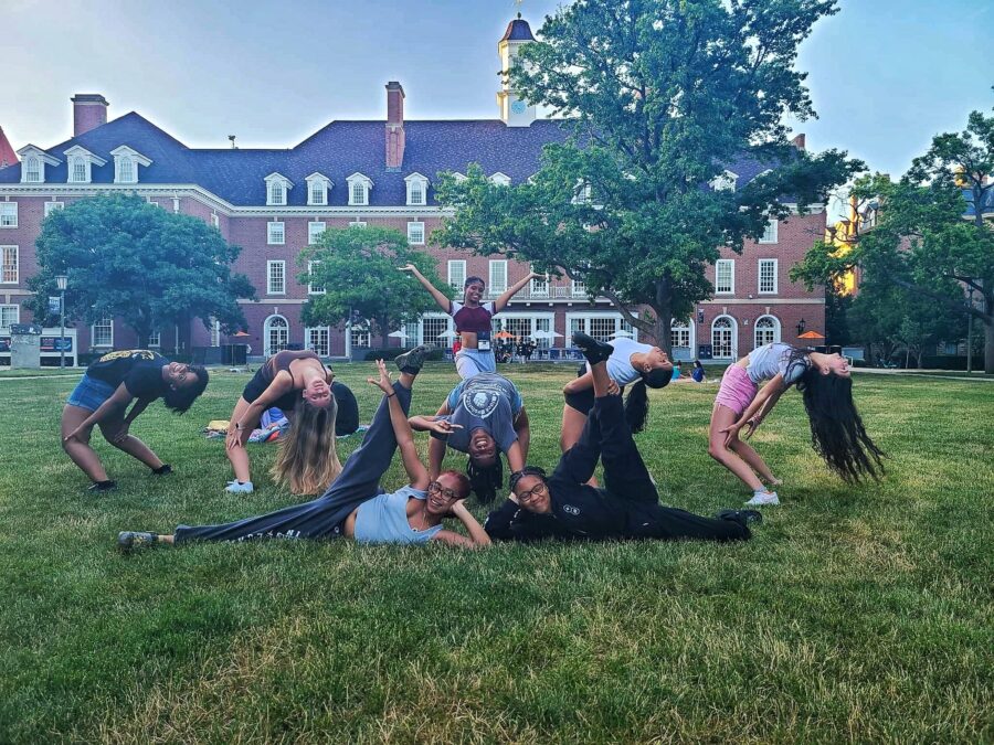 students in grassy main quad in dance poses