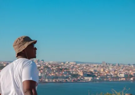 person in hat looking out over body of water