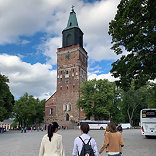 3 students' backs and a tall steeple