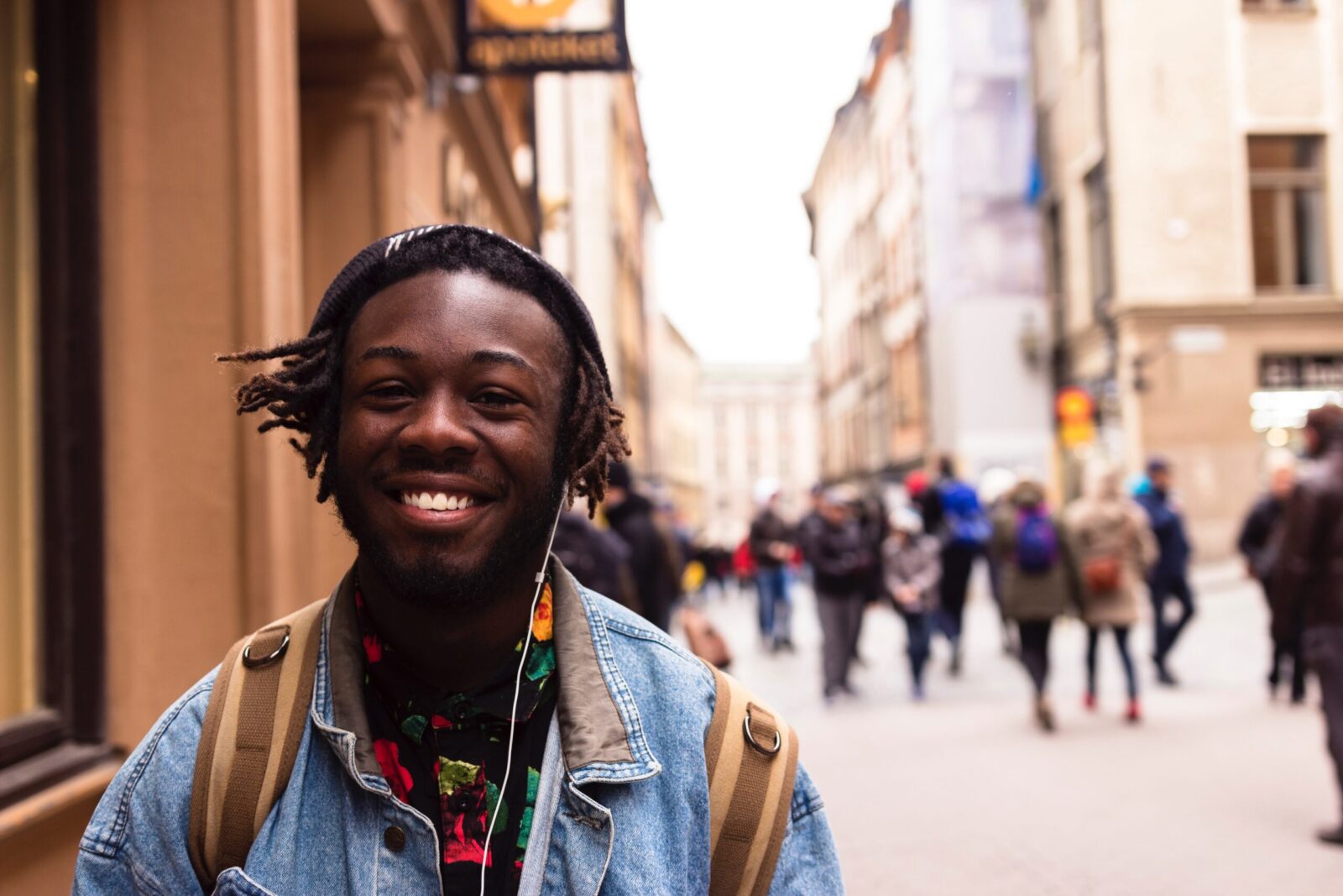student smiling with headphones on in the street
