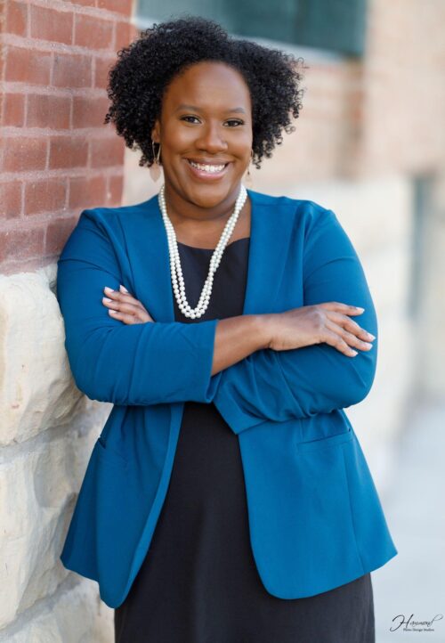 Mariam Thiam standing against brick wall with arms crossed