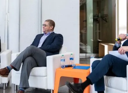 3 people sitting in chairs speaking into mics and smiling