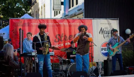 several people with instruments and microphones on an outdoor stage