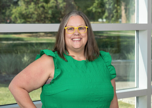 Person smiling with yellow glasses and green shirt