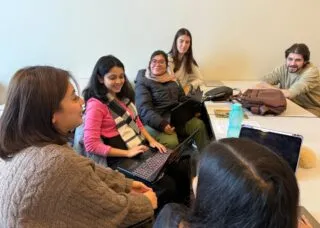 people gathered around a table with laptops