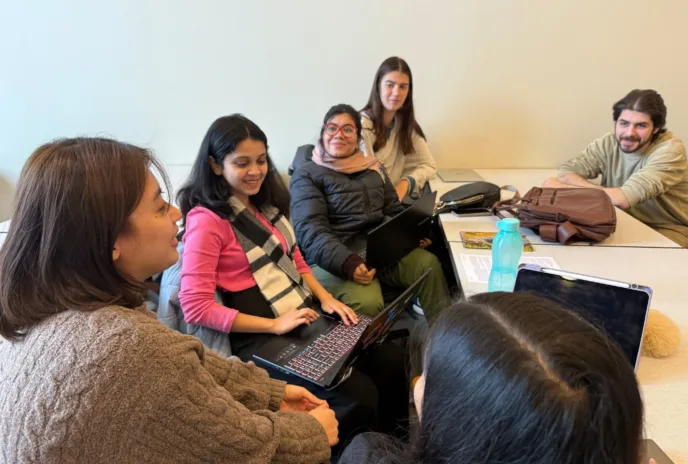 people gathered around a table with laptops