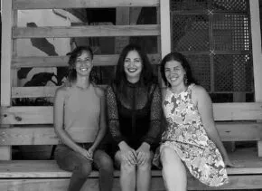 three people sitting on a wooden porch