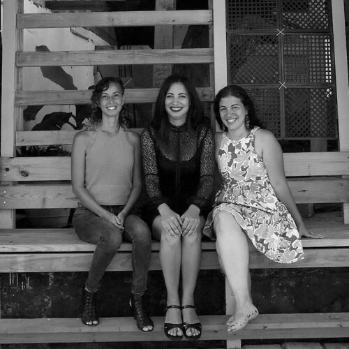 three people sitting on a wooden porch