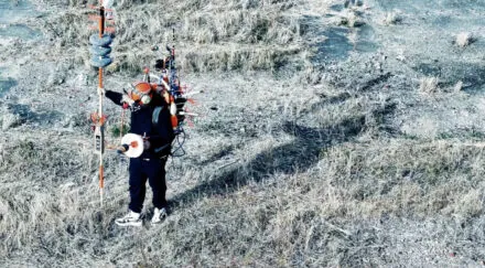 person walks through grassy plain with technology