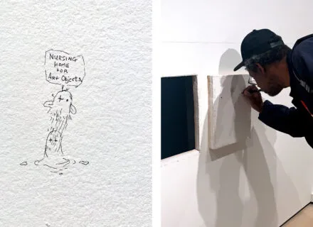 person leans over to draw on a white canvas currently hanging on a white wall
