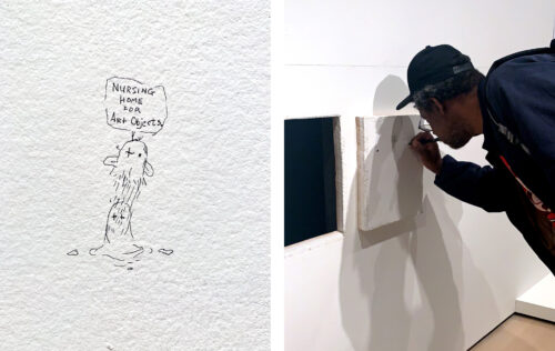 person leans over to draw on a white canvas currently hanging on a white wall