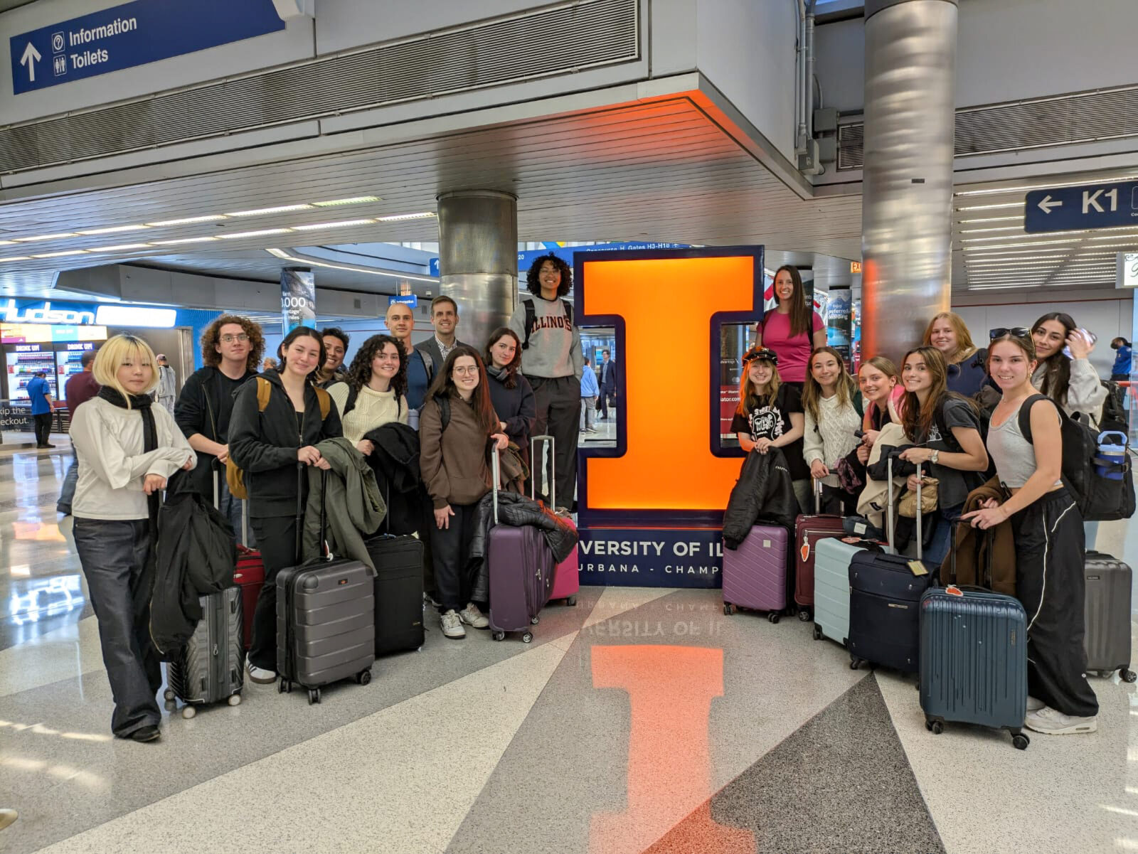 group of students with suitcases in airport surrounding block I