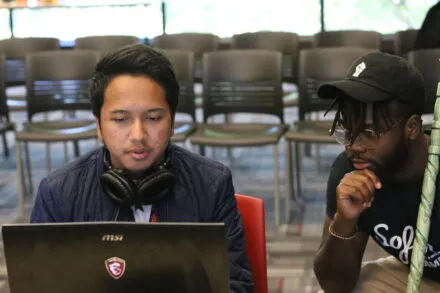 two people work on a laptop