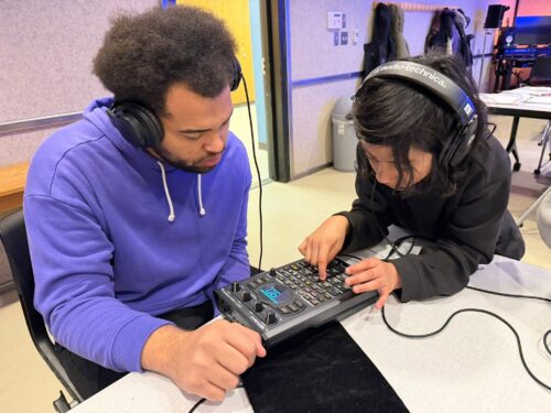 two people work on a sound board with headphones on