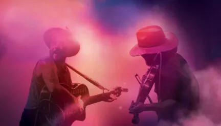 two people playing instrument under bright lights and stage fog
