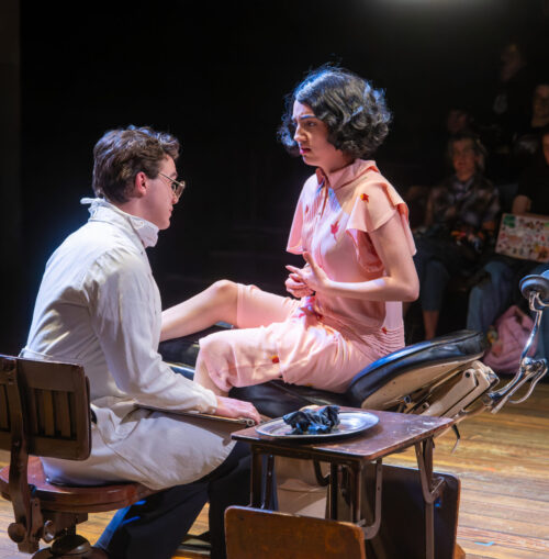 two people onstage with audience in the background