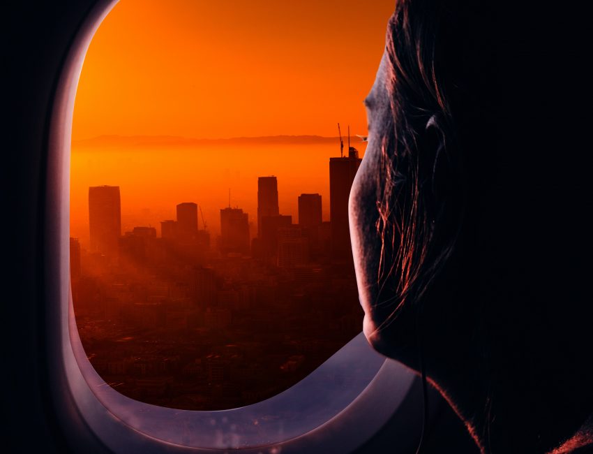 Woman looking out of an airplane window at a cityscape
