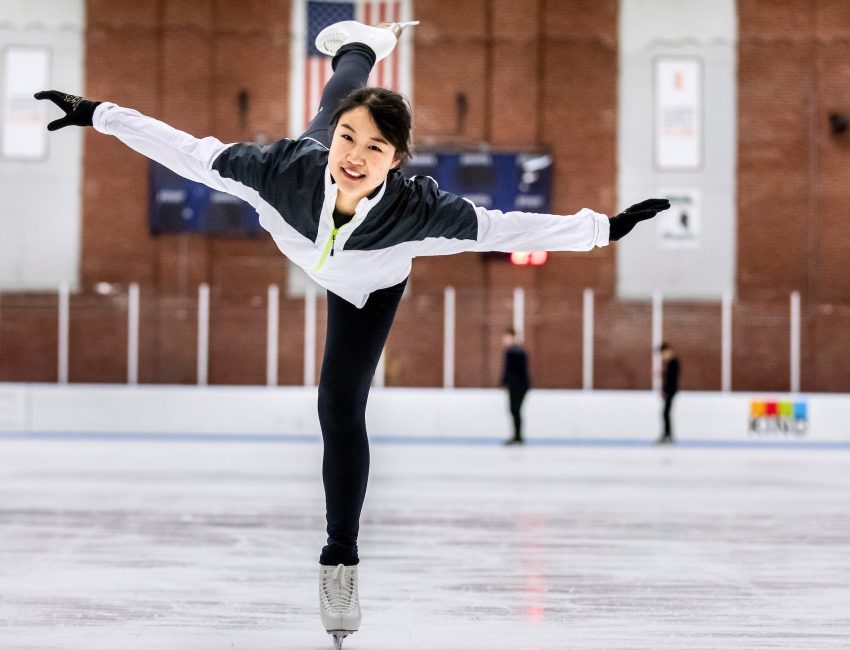 student ice skating on one foot with arms outstretched