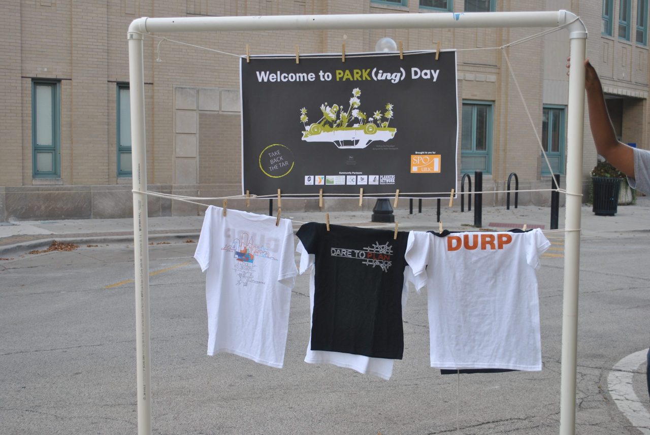 PARK(ing) Day sign in downtown Champaign, hanging over DURP t-shirts