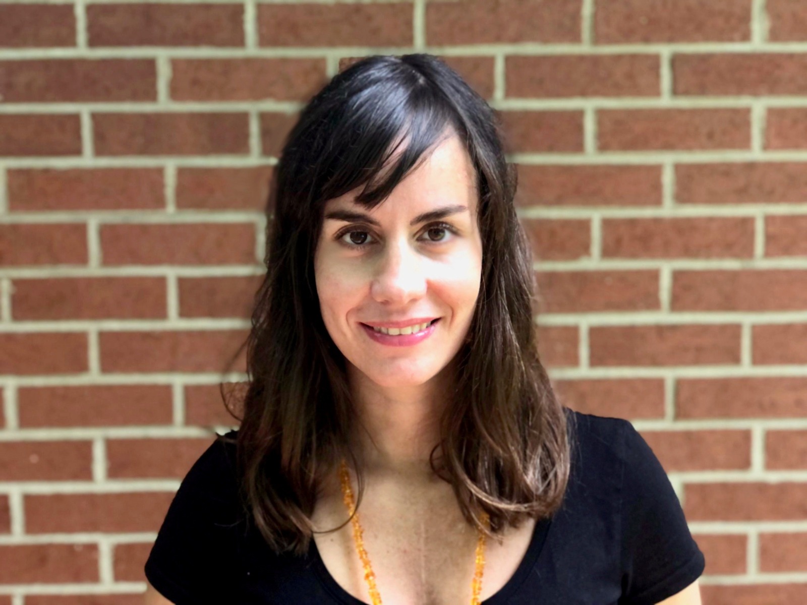 Photo of Professor Novoa in front of a red brick wall