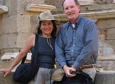 Photo of Doug and his wife Laura in front of an old white brick building