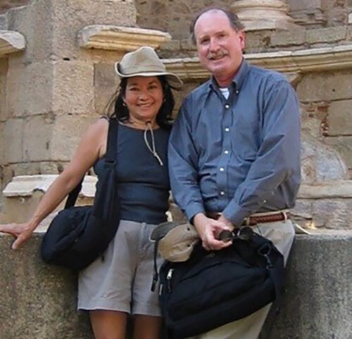 Photo of Doug and his wife Laura in front of an old white brick building