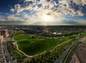 Aerial view of a town with green space in the center and a setting sun.