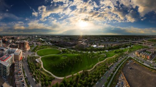 Aerial view of a town with green space in the center and a setting sun.