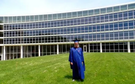 Drew Awsumb in cap and gown outside of TBH.