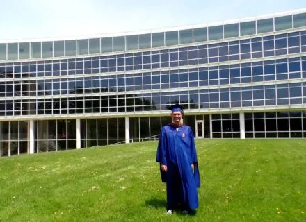 Drew Awsumb in cap and gown outside of TBH.