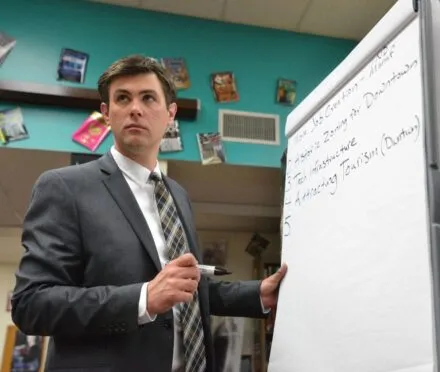 Photo of Drew Awsumb in front of a white board during a presentation.